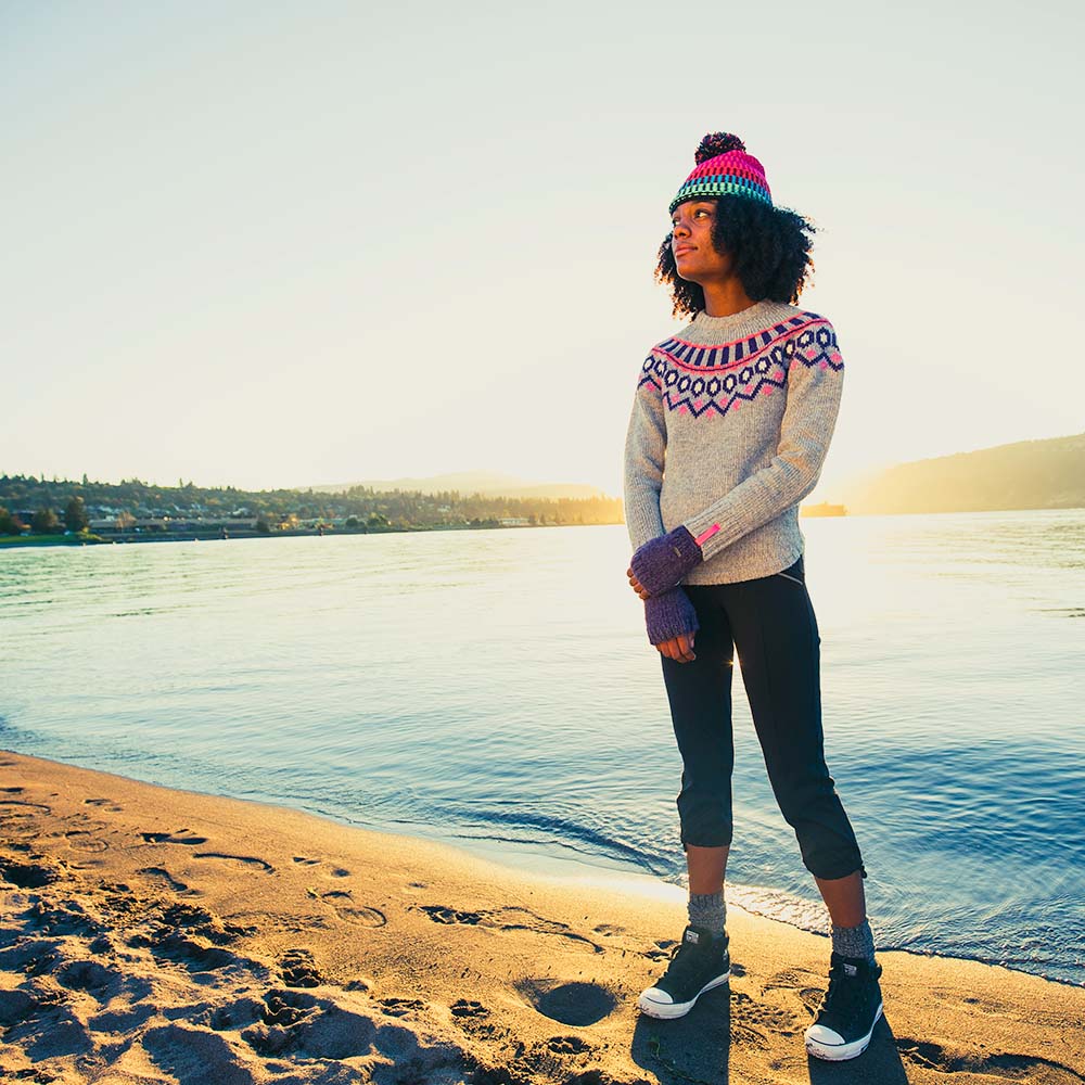 Pistil model standing on the beach wearing a beanie and gloves.